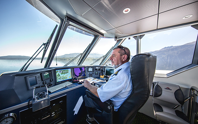 Real Journeys' worker at the helm of one of the company's vessels.