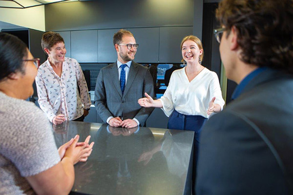 Photo of group of men and women in discussion in Kensington Swan office