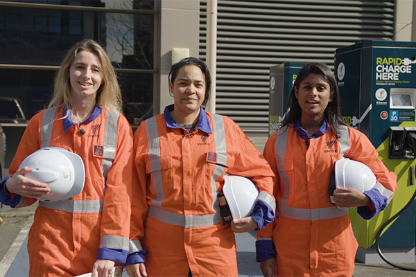 Photo of three female Vector staff members in overalls carrying hard hats