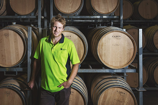 Photo of Constellation Brands New Zealand worker standing in front of wine barrels.