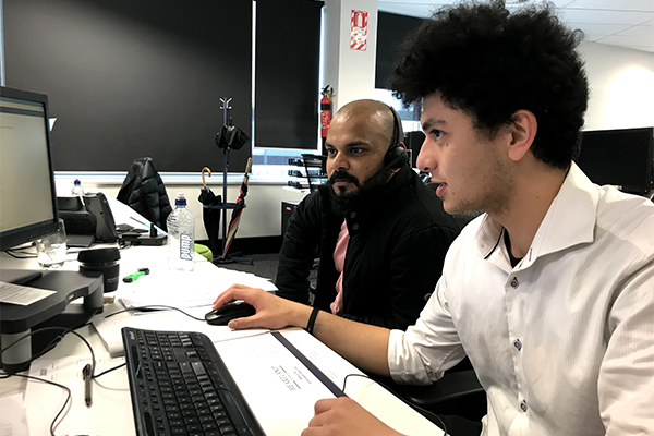 Photo of two men working together at a computer