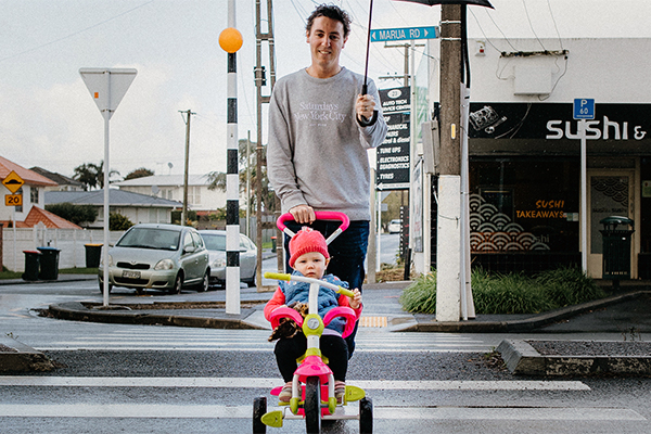 photo of father pushing child on toy bike