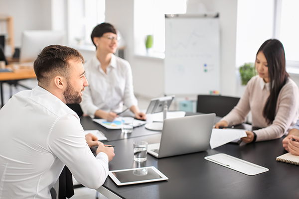 Men and women sitting around meeting room table