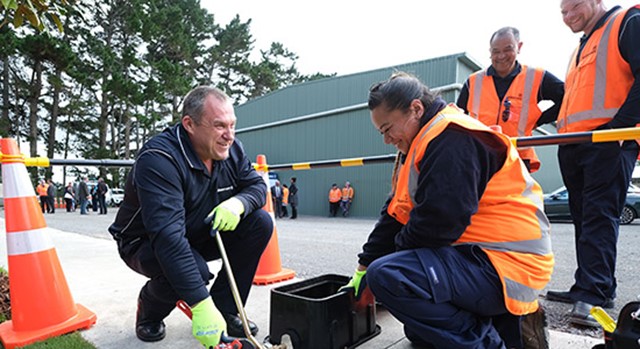 Photo of Citycare team, one woman in high-vis vest and three men working together on training exercise