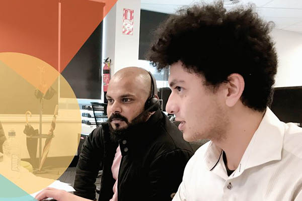 Photo of young man working alongside older man at computer taken from the cover of the 2021 New Zealand Workplace Diversity Survey report