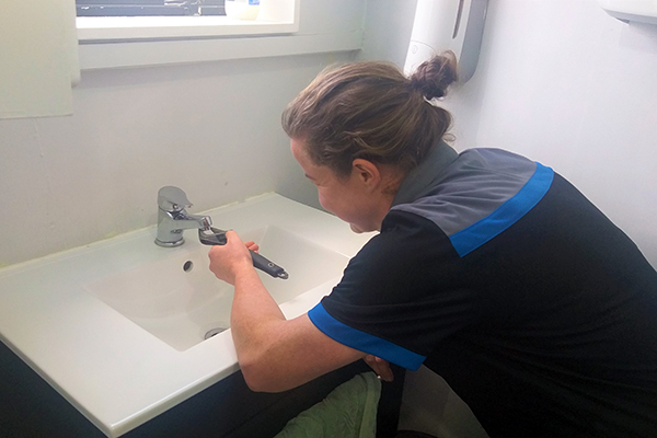 Female plumber works on tap