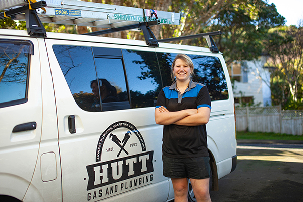 Female plumber stands in front of van