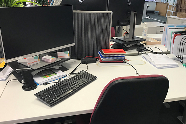 Desk with computer and notebooks but no one sitting at it