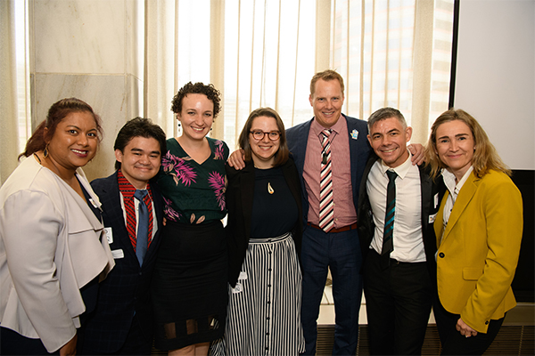 Six deaf staff, one hearing CEO, smiling arm-in-arm