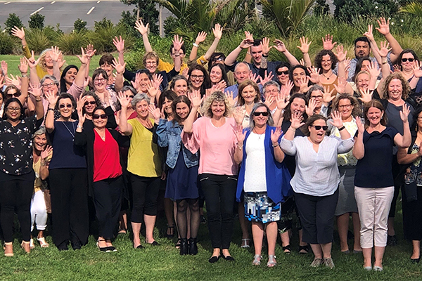 Large group of people waving in NZ Sign Language