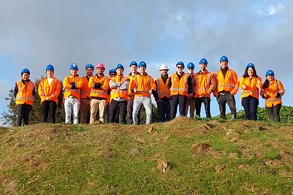 Construction workers in high-vis and hard hats, standing on hill