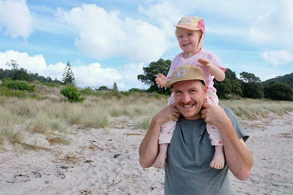 Man with toddler on shoulder at beach