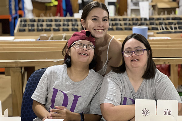 Candlemakers with downs syndrome smiling behind candles