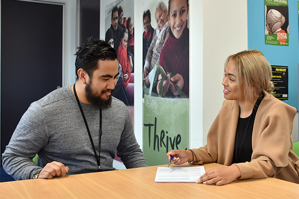 A Pacific man and woman smiling, working together at a table