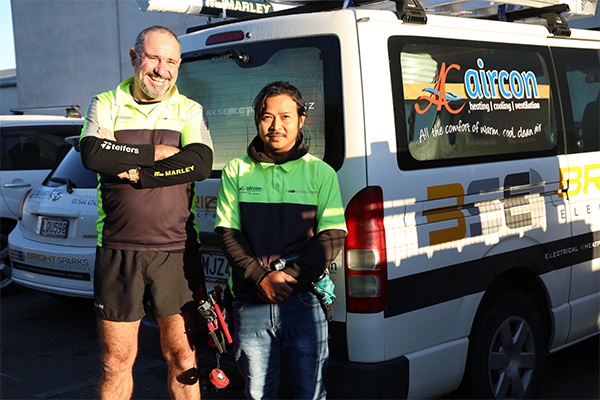 Two migrant tradies in front of van