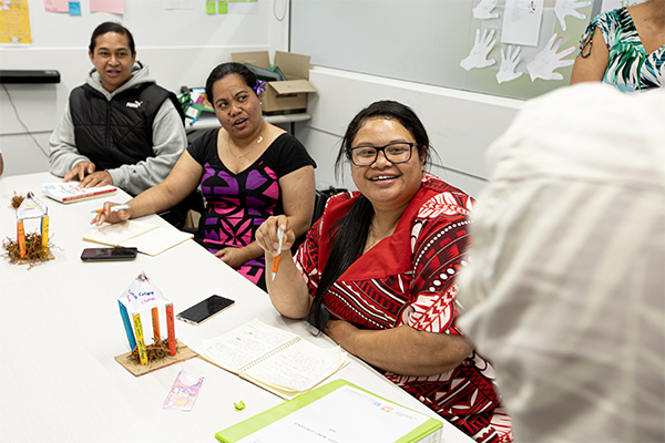 Three Pacific women writing at table