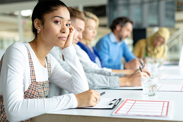 Woman at table with co-workers, looking frustrated