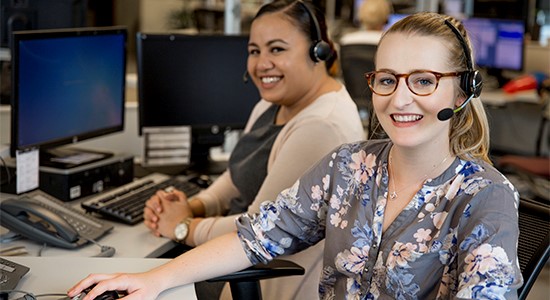 Two young women working at desks at a call centre