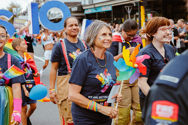 Range of people dressed colourfully, walking in a pride parade