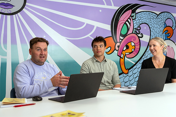 Workers at laptops in front of mural