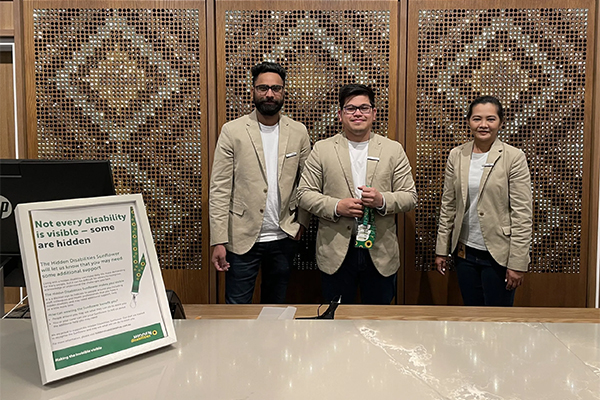 Staff behind hotel front desk with accessibility sign