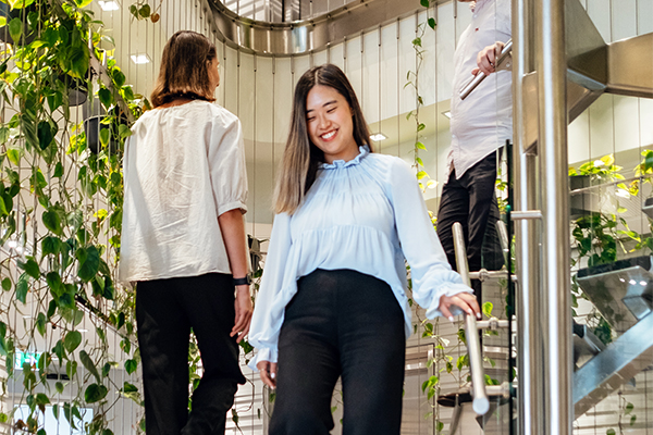 Colleagues smiling as they pass each other on stairs