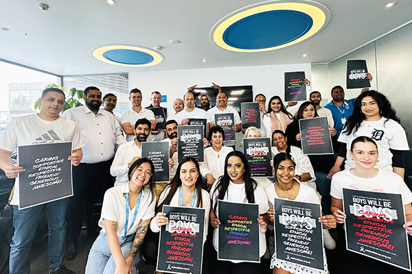 A group of staff holding signs promoting good behaviour for men on White Ribbon Day